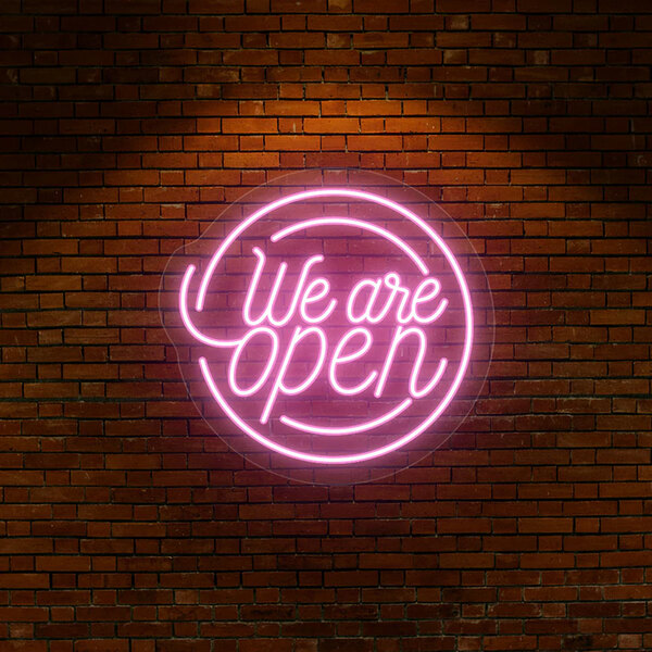 A pink "We Are Open" neon sign on a brick wall.