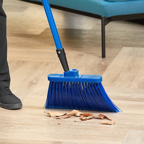 A person sweeping a wood floor with a blue Lavex angled broom.