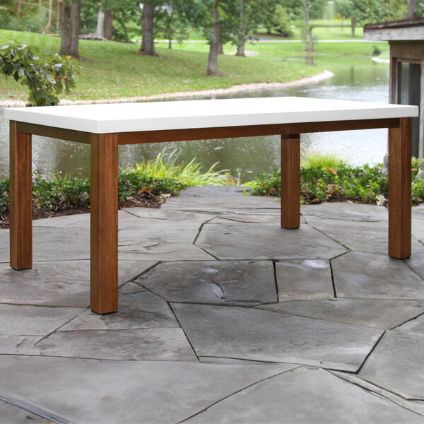 An ivory table with a wooden top on a stone patio.