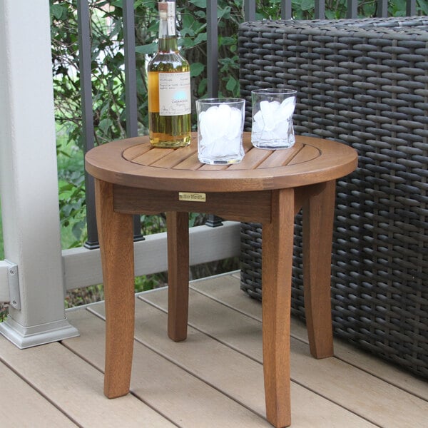 An Outdoor Interiors eucalyptus end table on a deck with two glasses of ice on it.