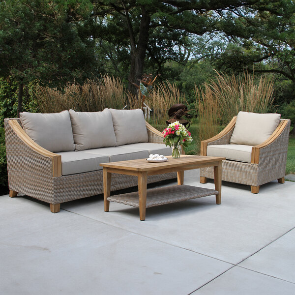 An Outdoor Interiors teak and ash wicker 3-seater sofa and table on a patio.