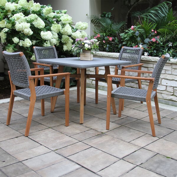 An Outdoor Interiors gray rope and eucalyptus stackable chair and table on a patio.