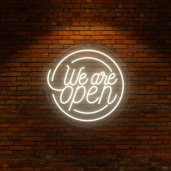 A warm white neon "We Are Open" sign on a brick wall.