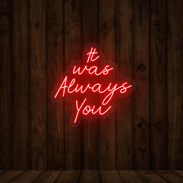 A red Crazy Neon "It Was Always You" LED sign on a wood wall.