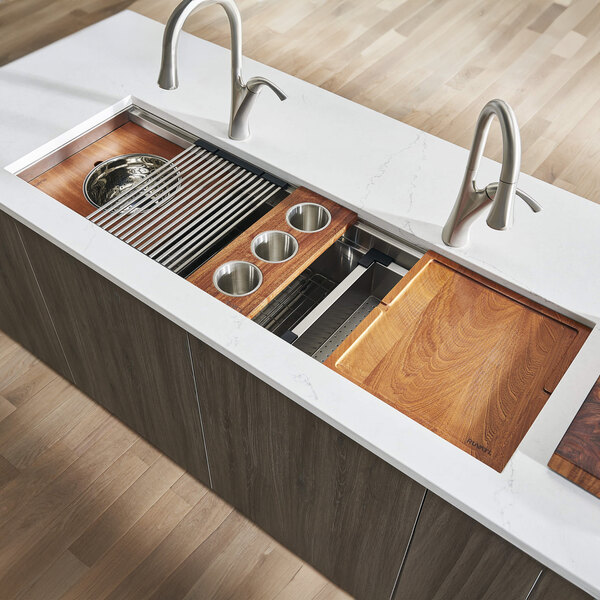 A Ruvati stainless steel workstation sink with wood tray and cutting board accessories.