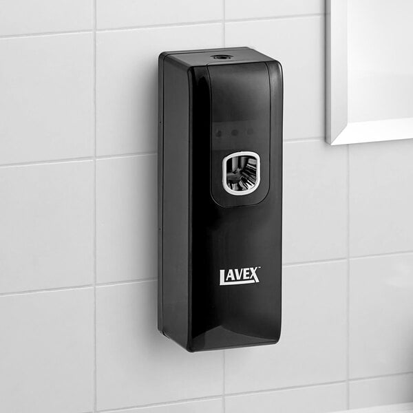 A black Lavex rectangular aerosol air freshener system on a white tile wall.