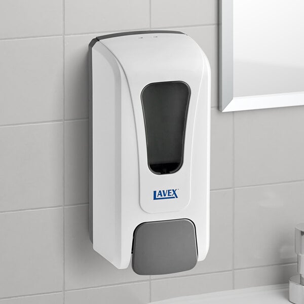 A white rectangular Lavex manual liquid soap dispenser with a transparent window on a tile wall.