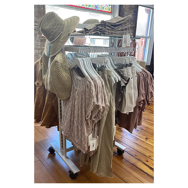 A white UDIZINE retail clothing display stand with clothes and hats on it.