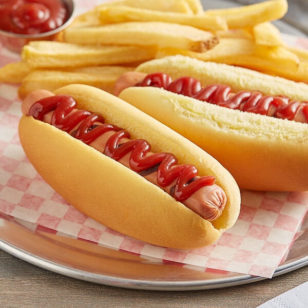 Two Martin's Famous hot dogs on sliced potato rolls with ketchup on a table in a stadium concession stand.