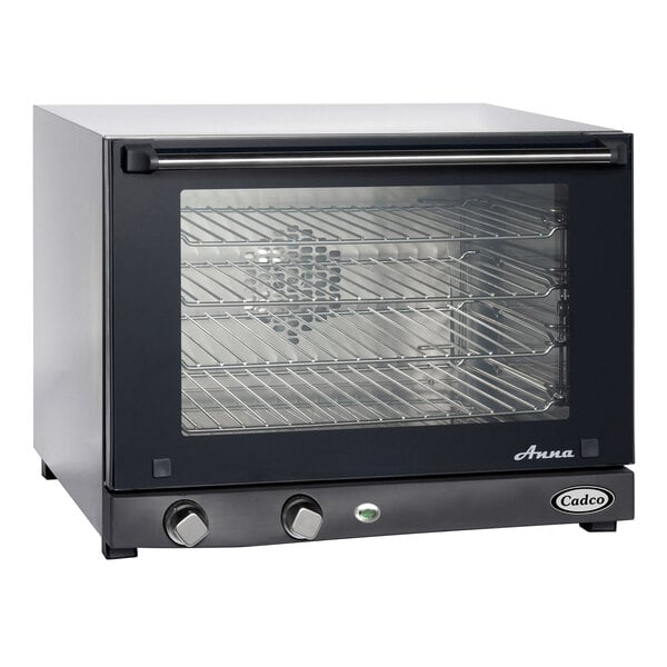 A black and silver Cadco Countertop Convection Oven with a glass door and a rack of food inside.