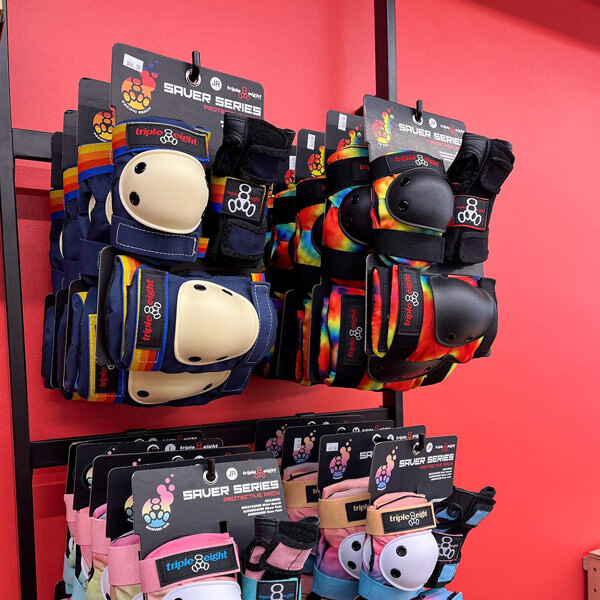 A UDIZINE black wall-mounted retail clothing display with hanging rails and hooks holding wrist and knee guards.