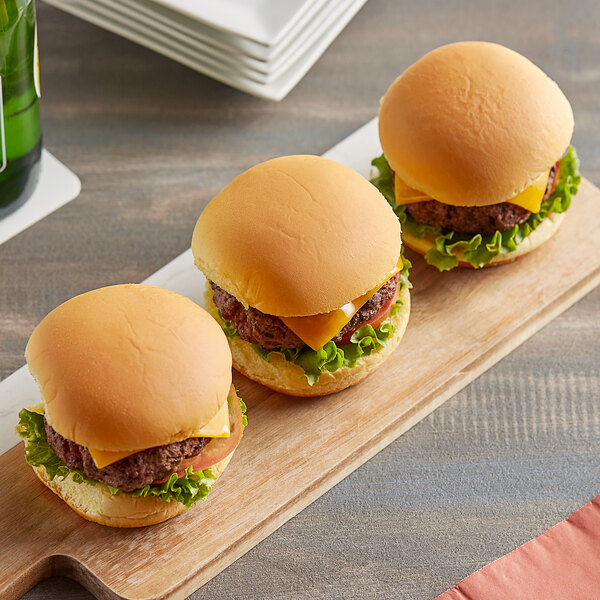 Three Martin's potato rolls with hamburgers on a wooden board.