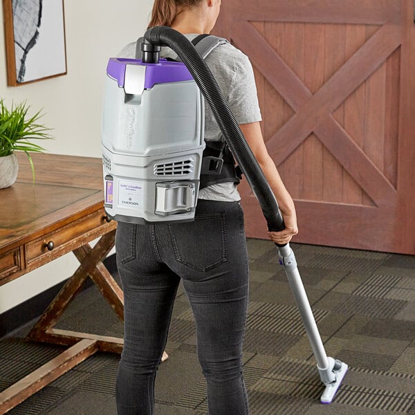 A woman using a ProTeam GoFit 3 cordless backpack vacuum to clean a floor.