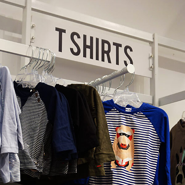 A white UDIZINE side sign on a rack of clothes.