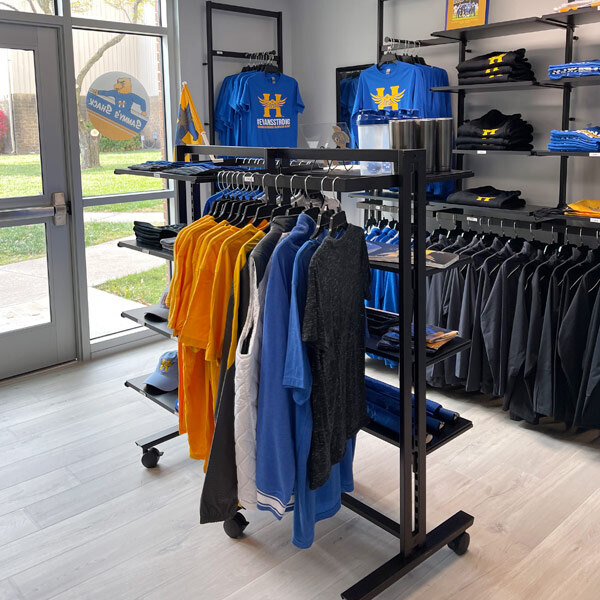 A black Udizine mobile retail clothing rack with clothes on it.