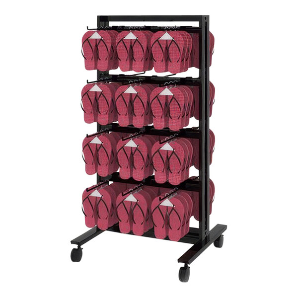 A black Udizine mobile retail clothing display stand with hooks holding red flip flops.