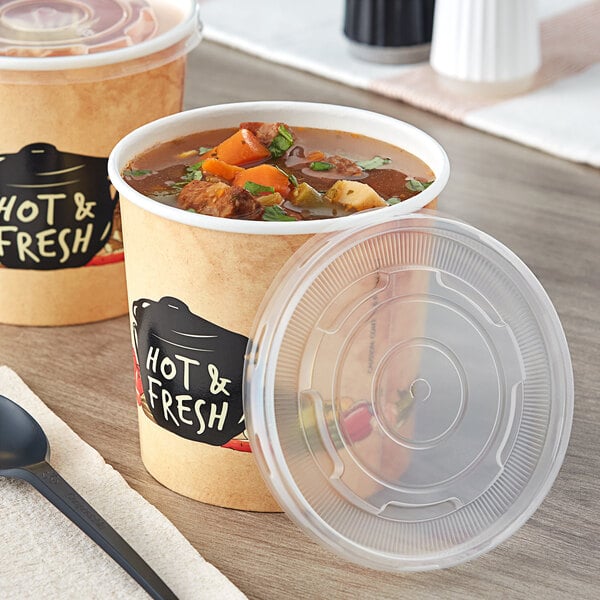 Choice paper soup containers with plastic lids on a table.