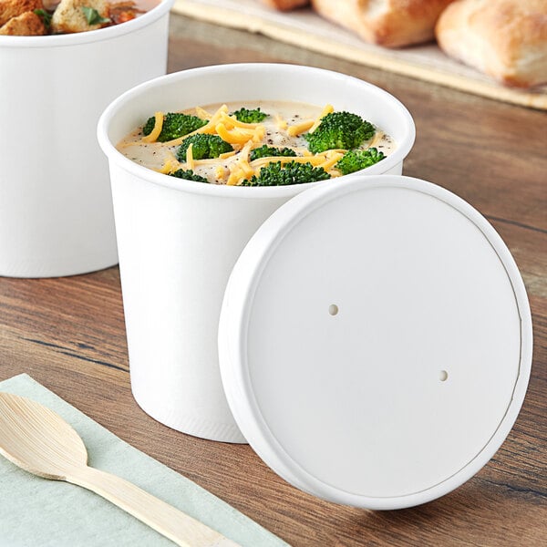 Two white paper food containers filled with soup and topped with a white paper lid.