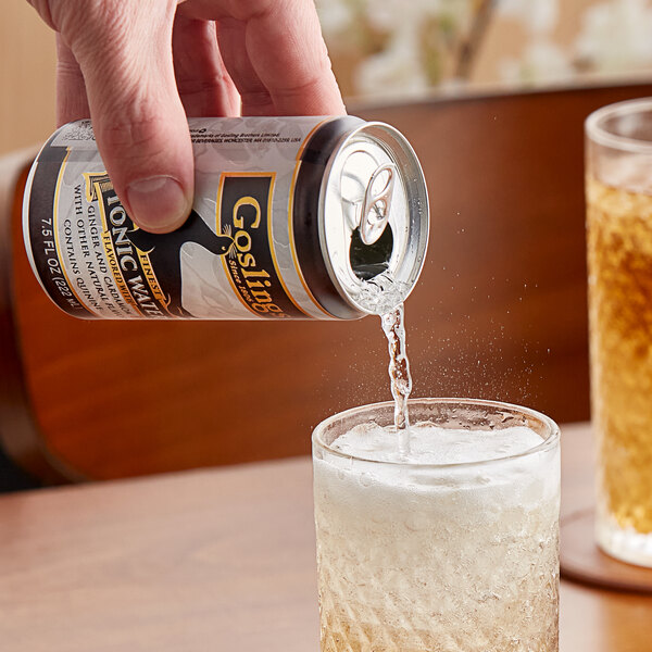 A hand pouring Goslings Finest Ginger Tonic Water from a can into a glass of liquid.