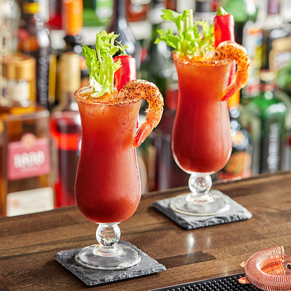 Two glasses of Zing Zang Bloody Mary with shrimp garnish on a bar.