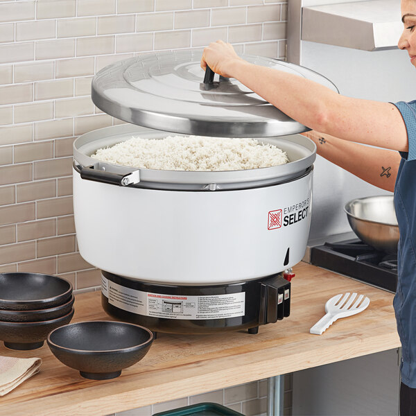 A woman using an Emperor's Select gas rice cooker to prepare rice.