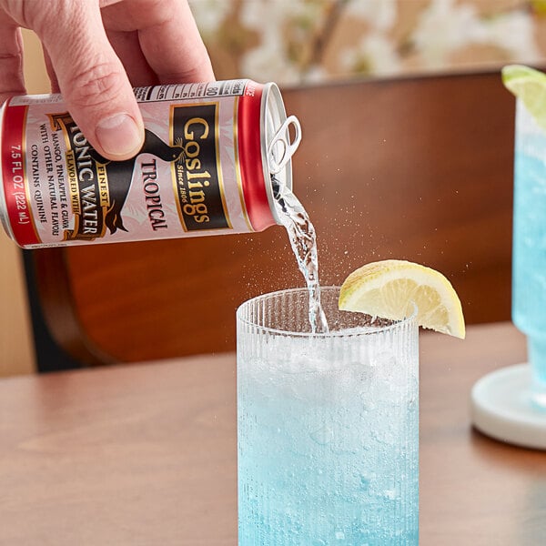 A hand pouring Goslings Finest Tropical Tonic Water into a glass.