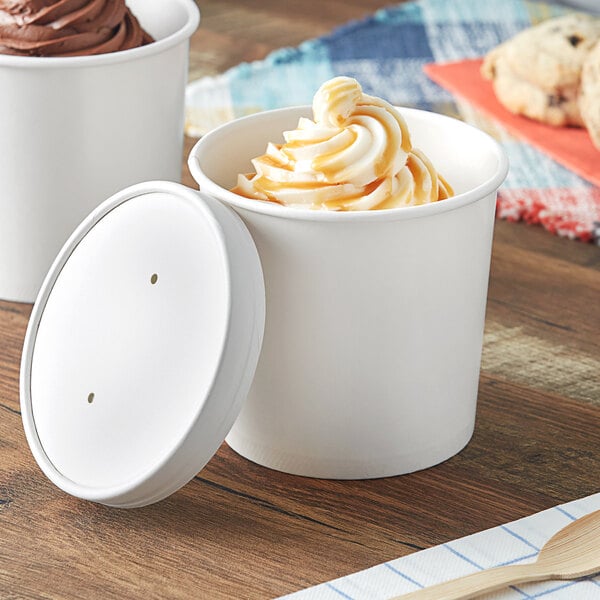 Two Choice white paper food cups filled with ice cream and topped with a vented paper lid.