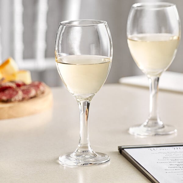 Two Acopa Bouquet wine glasses on a table with pizza and wine.