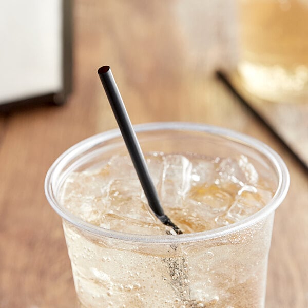 A black EcoChoice PLA straw in a glass on a table with ice and liquid.