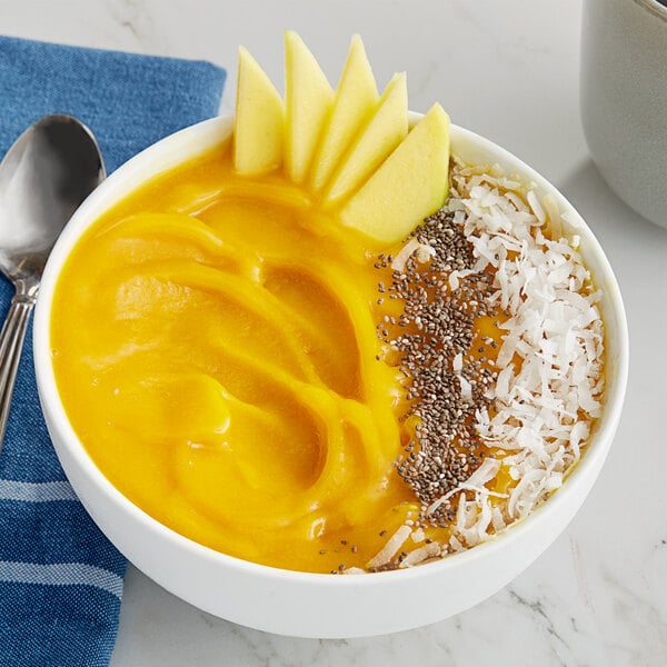 A bowl of Tropical Acai Mango Sorbet with fruit and coconut flakes on a counter.