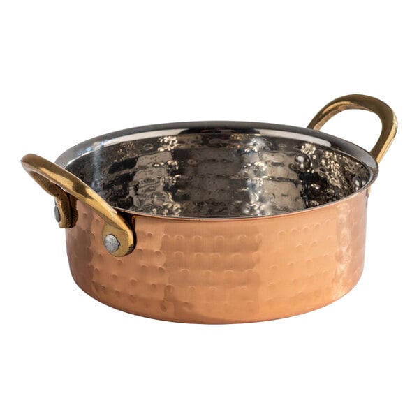 An APS Mumbai round hammered copper serving pot with two handles.