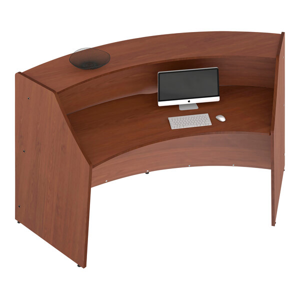 A cherry laminate curved reception desk with a computer and monitor.