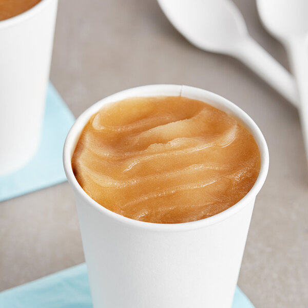 A cup of I. Rice Churro Water Ice on a table with spoons.