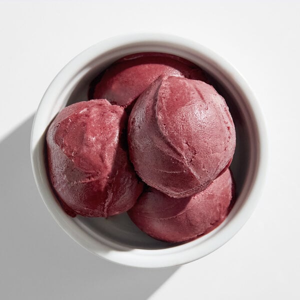 A bowl containing several scoops of dark purple acai sorbet.