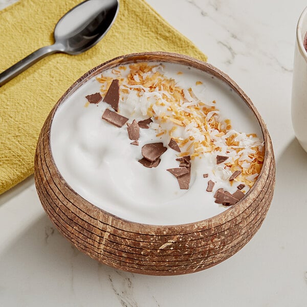 A bowl of white Tropical Acai coconut sorbet with chocolate shavings and a spoon on a yellow cloth.