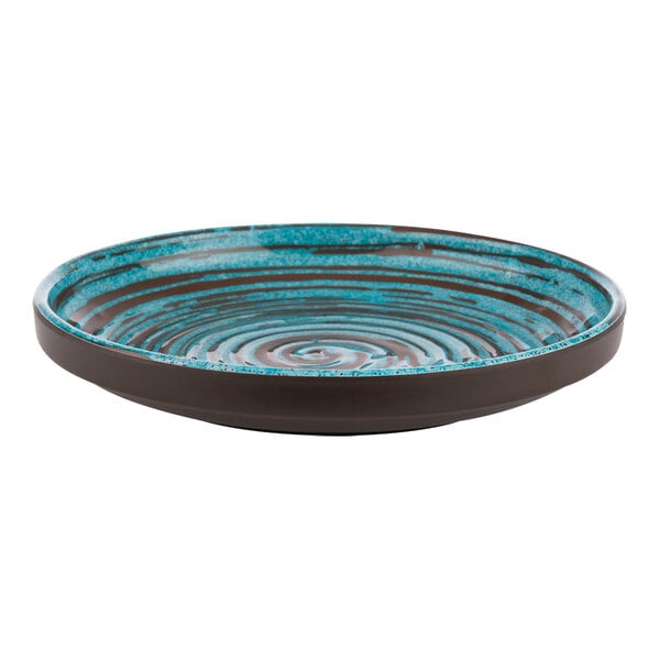 A blue and brown APS Cancun melamine plate with a water ripple design on a table on an outdoor patio.