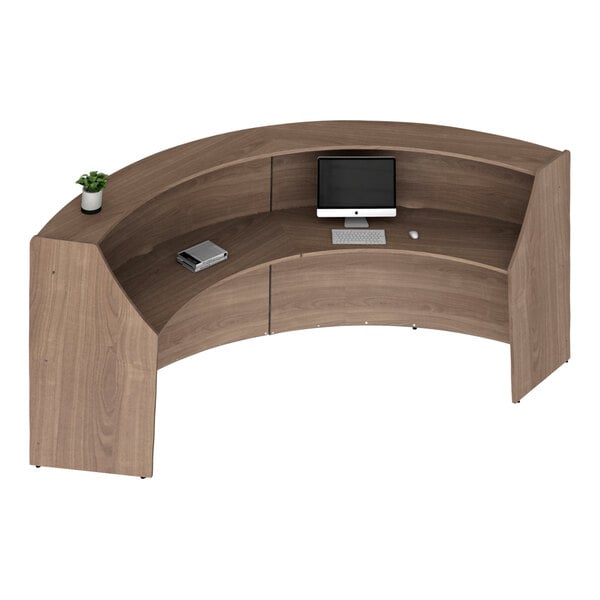 A walnut laminate curved reception counter with a computer and monitor on it.