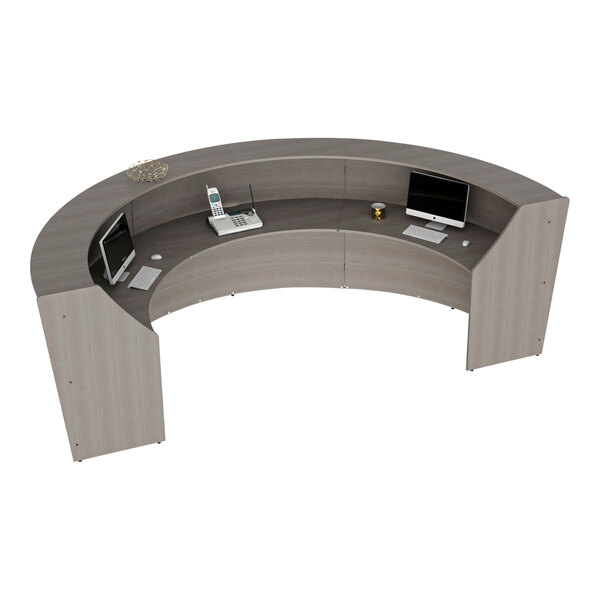 A 3 panel curved reception desk with computers and a telephone on it.
