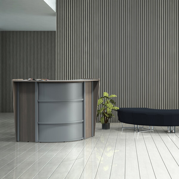 A walnut laminate curved corner reception desk with a plant in a pot on it.