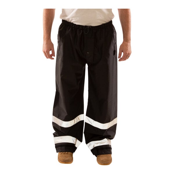 A man wearing Tingley black pants with reflective tape on the legs.