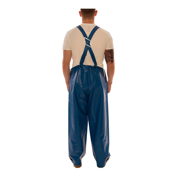 A person wearing blue Tingley Eclipse overalls with white tape on the back.