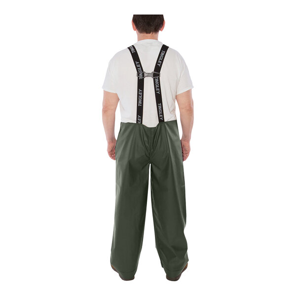 A man wearing Tingley green rain overalls and suspenders over a white shirt.