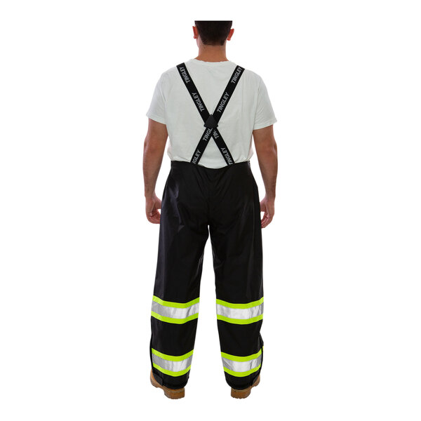 A man wearing black Tingley Icon overalls and black suspenders over a white shirt.