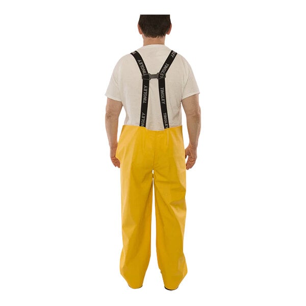 A man wearing Tingley yellow rain overalls with suspenders.