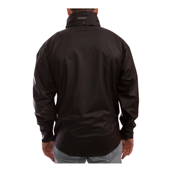 A man wearing a black Tingley StormFlex rain jacket with a hood.