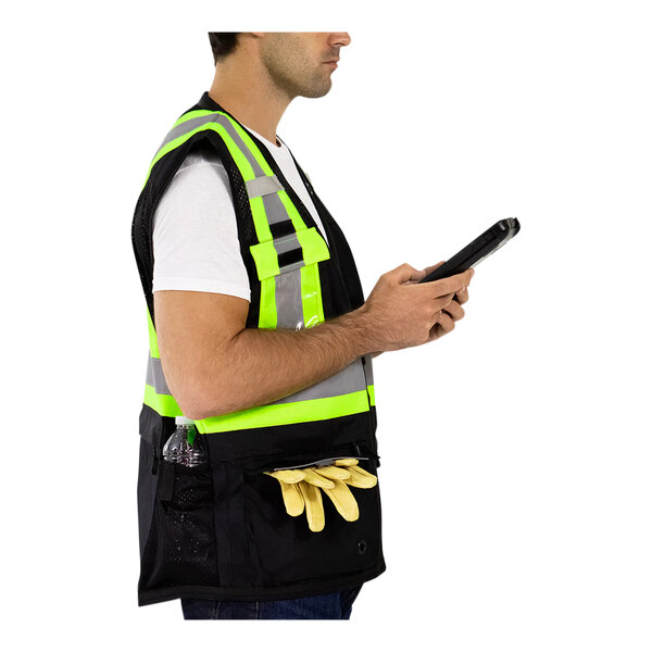 A man in a Tingley black and yellow reflective safety vest using a tablet.