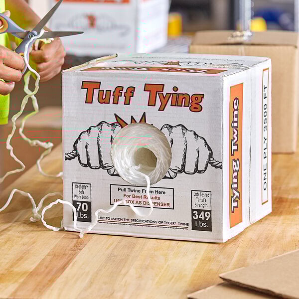A person cutting 1-Ply Polypropylene Industrial Twine with scissors.