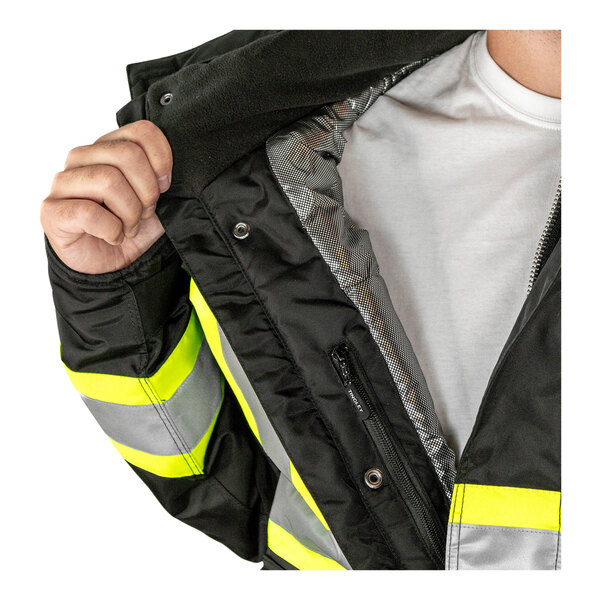 A person holding a black Tingley Cold Gear industrial work jacket with silver reflective stripes.