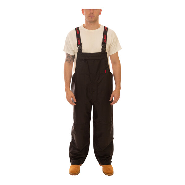 A man wearing Tingley black overalls.