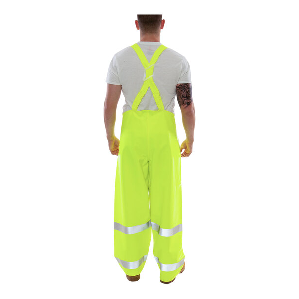A man wearing Tingley yellow safety overalls with hands on hips.